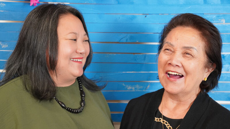 Fundholders Sharon and Bee smiling against a blue backdrop